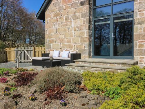 a brick house with a couch on a patio at Woodend Croft in Ellon