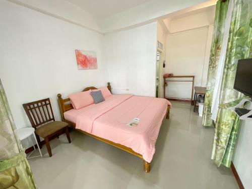 a bedroom with a pink bed and a chair at บ้านสุขอรุณ เขาค้อ Baan Sook A Roon KhaoKho in Khao Kho