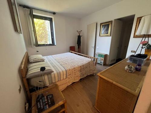 a bedroom with a bed and a desk and a window at Casa fronte lago con piscina in Angera