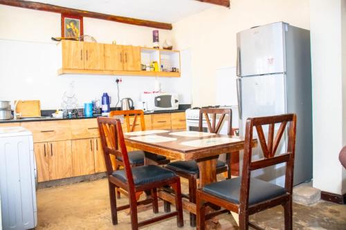 La cuisine est équipée d'une table, de chaises et d'un réfrigérateur. dans l'établissement Stone Camp Naivasha, à Naivasha