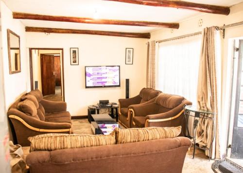 a living room with couches and a flat screen tv at Stone Camp Naivasha in Naivasha