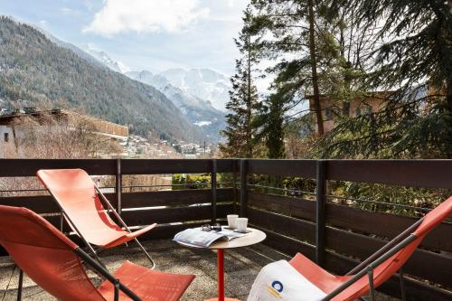 two chairs and a table on a balcony with mountains at SOWELL HOTELS Mont Blanc et SPA in Saint-Gervais-les-Bains