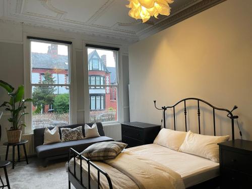 a bedroom with a bed and a couch and a window at Deluxe Huge Detached House with Parking, sleeps up to 30 people, 2m from Liverpool City Centre in Liverpool