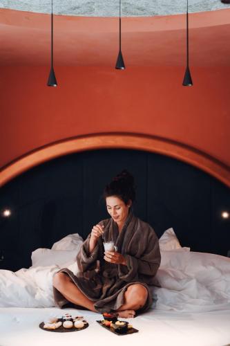 a woman in a robe sitting on a bed at Latemar - Hotel Suites Spa in Soraga