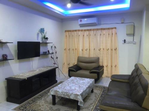 Salak Indah Homestay KLIA/KLIA2 في سيبانغ: غرفة معيشة مع أريكة وكراسي وتلفزيون