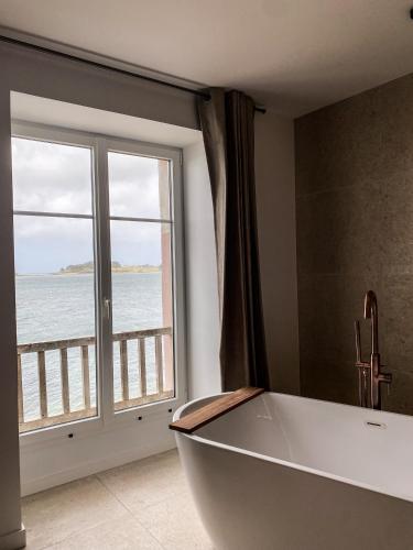 une baignoire dans une salle de bain avec une grande fenêtre dans l'établissement ILE CEZON - Duplex de luxe avec magnifique vue mer, à Landéda