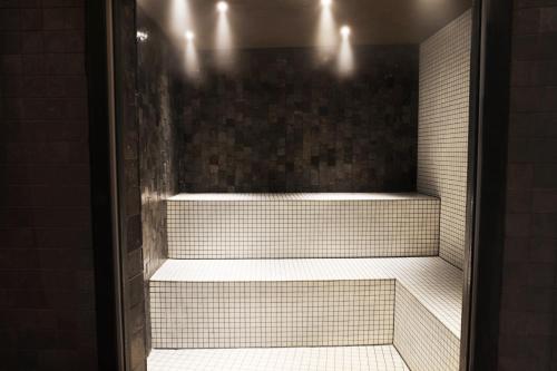 a walk in shower with white tiles and lights at Hotel Reykjavík Saga in Reykjavík