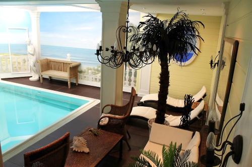 a living room with a pool and a table and a palm tree at Parkhotel Fischer in Wernigerode