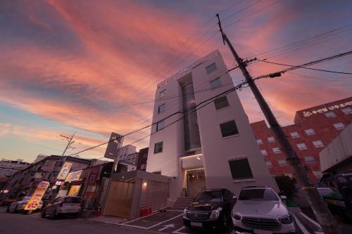 a building with cars parked in a parking lot at Aank Hotel Osan in Osan