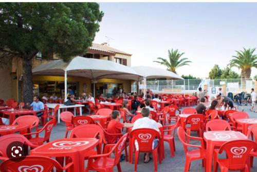 un groupe de personnes assises à des tables et des chaises rouges dans l'établissement Mobilhome 6 places, à Vic-la-Gardiole