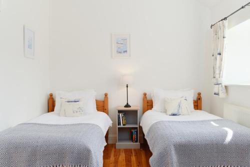 two beds sitting next to each other in a bedroom at Cobblestone Cottage in Penzance