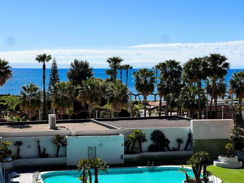 uma vista para uma piscina com palmeiras e para o oceano em Tropical y Lujoso Complejo em Oropesa del Mar