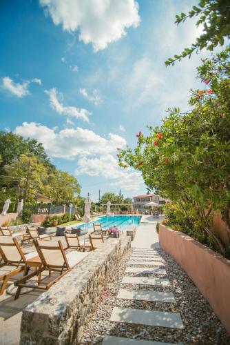 a pool at a resort with chairs and trees at Dominoes Corfu in Ýpsos