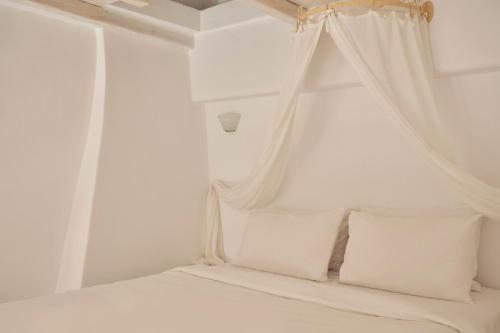 een wit bed met witte kussens en een baldakijn bij Town Mansion by Monocle in Mykonos-stad