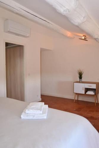 a bedroom with a white bed and a table at L'Atelier Appartement au cœur du vignoble in Rognes