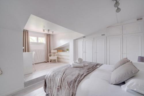 een witte slaapkamer met een groot bed en een stoel bij La Casa Bohème - Superbe maison avec parking privé in Bordeaux