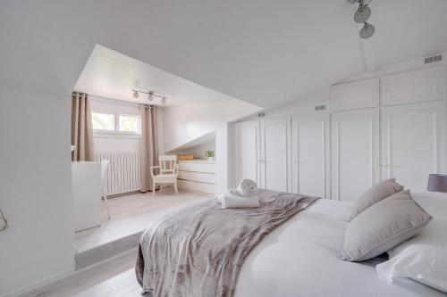 biała sypialnia z dużym łóżkiem i krzesłem w obiekcie La Casa Bohème - Superbe maison avec parking privé w mieście Bordeaux