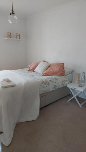 a white bedroom with a bed and a table at AROHA in Glastonbury