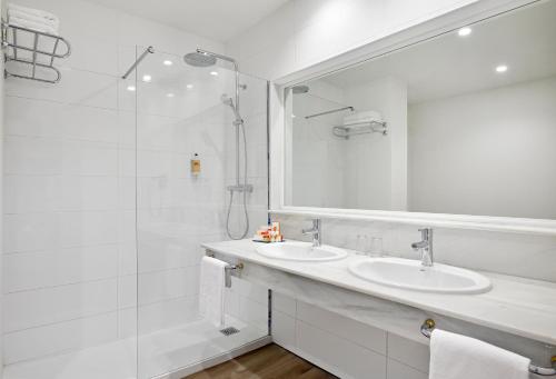 a white bathroom with two sinks and a shower at Sol Marbella Estepona Atalaya Park in Estepona