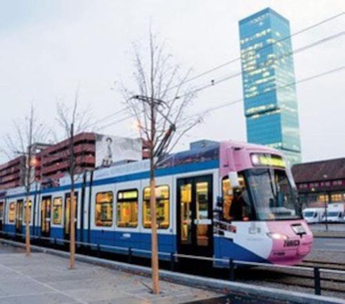 a pink and blue train traveling down the tracks at Wohnung im Trendquartier zentral - 24-7 check-in with keybox in Zürich