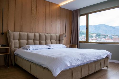 a bedroom with a large bed with a large window at Bocca Hotel Korce in Korçë