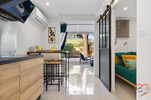 Il comprend une cuisine et un salon avec un canapé vert. dans l'établissement Cookie Love - entièrement neuf - à 100 m de l'entrée du village naturiste, au Cap d'Agde