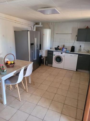 une cuisine avec une table et des chaises et une cuisine avec un lave-linge dans l'établissement Chez mamie, à Saint-Étienne-du-Grès