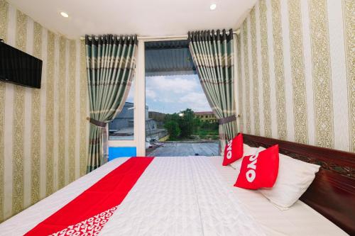 a bedroom with a bed with red pillows and a window at OYO 1117 Ngoc Lan Motel in Hue
