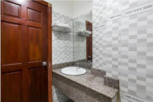 a bathroom with a sink and a brown door at OYO 1117 Ngoc Lan Motel in Hue