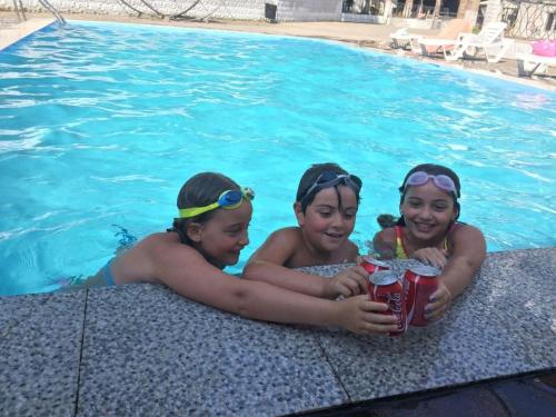 three girls are sitting in a swimming pool at Hotel Nine Brothers in Batumi