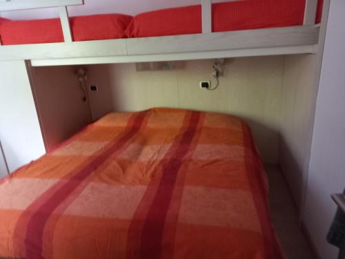 a bed in a small room with red and orange blankets at Riva del Garda in Riva del Garda