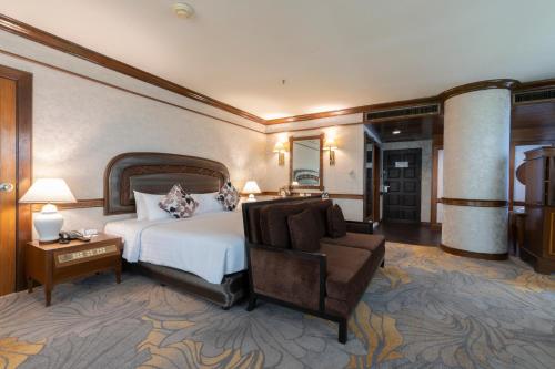 um quarto de hotel com uma cama e uma cadeira em The Twin Lotus Hotel em Nakhon Si Thammarat