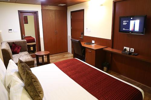 a hotel room with a bed and a flat screen tv at Hotel Cama in Chandīgarh