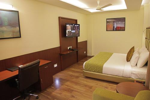 a hotel room with a bed and a desk with a computer at Hotel Cama in Chandīgarh
