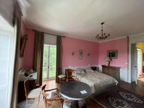 1 dormitorio con paredes rosas, 1 cama y 1 mesa en Château de Grandval, en Neuville-au-Plain