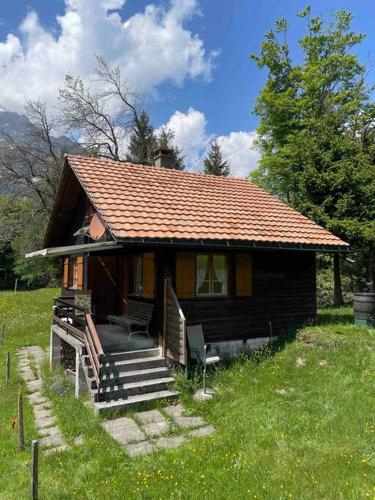 une petite maison avec une terrasse couverte et des escaliers. dans l'établissement Behagliches Chalet mit Kaminofen umgeben von Natur, à Glarus