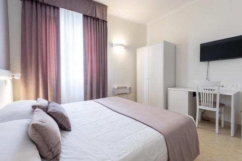 a bedroom with a white bed and a desk and a computer at Hotel Centrale Spa & Relax in Alcamo
