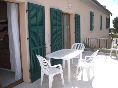 a table and chairs on a balcony with green shutters at Villa mit Whirlpool und phantastischer Aussicht in Capoliveri