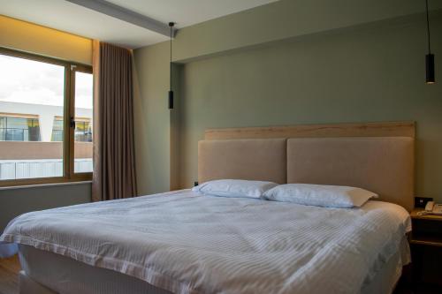 a bedroom with a bed with two pillows and a window at Bocca Hotel Korce in Korçë