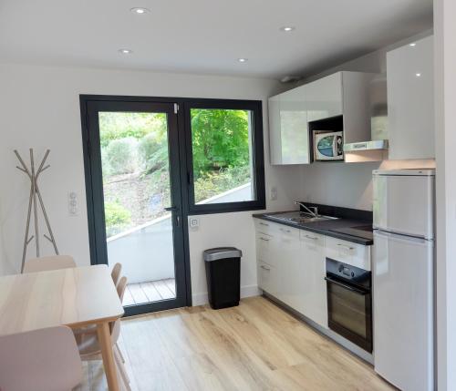 une cuisine avec des appareils blancs et une table avec des chaises dans l'établissement Agen - Location appartement 4 personnes à hossegor, à Soorts-Hossegor