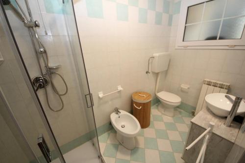 y baño con ducha, aseo y lavamanos. en Residence Verdena appartamento 02 en Rosolina Mare