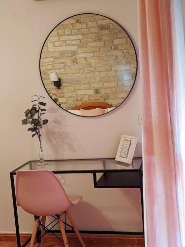 a desk with a pink chair and a mirror at Hotel Moregón in Cuacos de Yuste