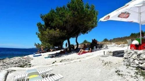 a beach with chairs and an umbrella and the ocean at Apartment Anita in Trogir