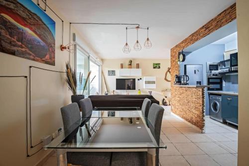 L'Odyssée, Appt 4 pers, parking privé, Wifi في مونبلييه: غرفة طعام ومطبخ مع طاولة وكراسي زجاجية