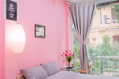 Habitación de color rosa con cama y ventana en Kim's Homestay Center of Ha Noi en Hanói