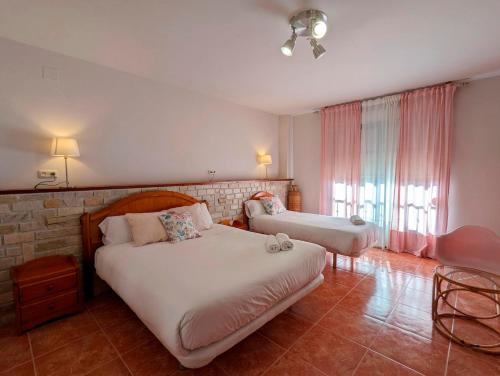 a bedroom with two beds and a brick wall at Hotel Moregón in Cuacos de Yuste