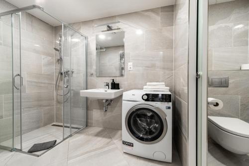 ein Badezimmer mit einer Waschmaschine und einem Waschbecken in der Unterkunft Apartments Harfa in Prag