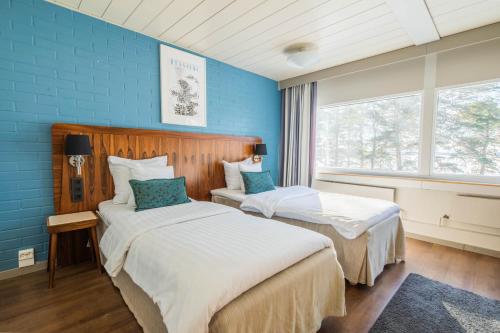 2 łóżka w pokoju z niebieskimi ścianami w obiekcie Hotel Rantapuisto w Helsinkach