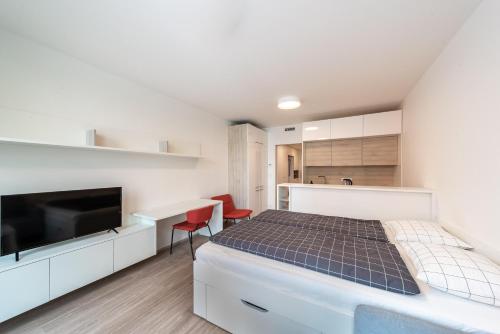 a white bedroom with a bed and a kitchen at Apartments Harfa in Prague