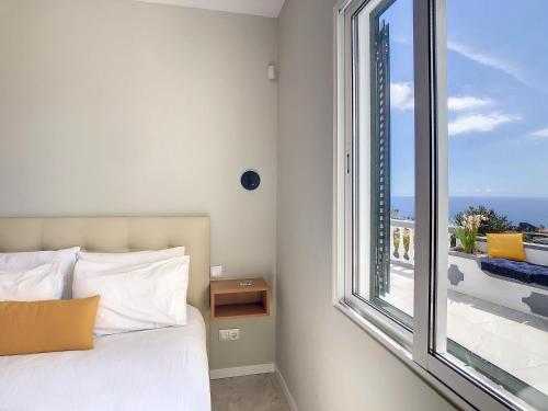 a bedroom with a bed and a large window at Avocado Villa by LovelyStay in Funchal